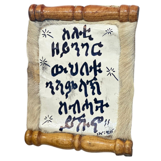 A leather fabric art with Tigrinya scripture text, mounted on a wooden wall art frame.