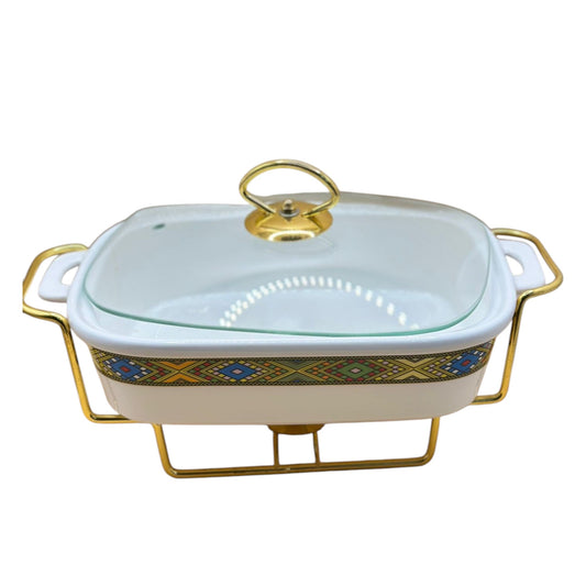 A traditional ceramic Habesah food server with a white base and gold and blue decorative patterns, equipped with a glass lid and a golden stand.
