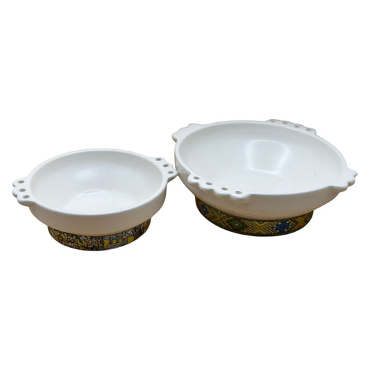 Two white ceramic Taba Habesha serving stew pots with gold and blue patterned bases.