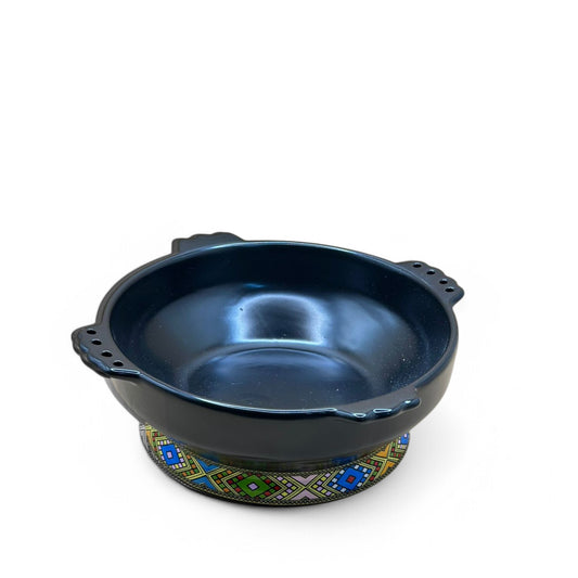 A black ceramic Taba pot with handles and a decorative pattern around the base.