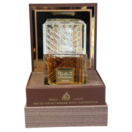 Perfume bottle with gold cap and Khamram branding on a brown display stand.