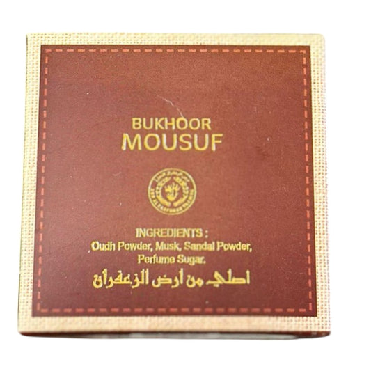 A box of Mousuf Bukhoor with ingredients listed on the packaging, including Oud Powder, Musk, Sandal Powder, and Perfume Sugar.