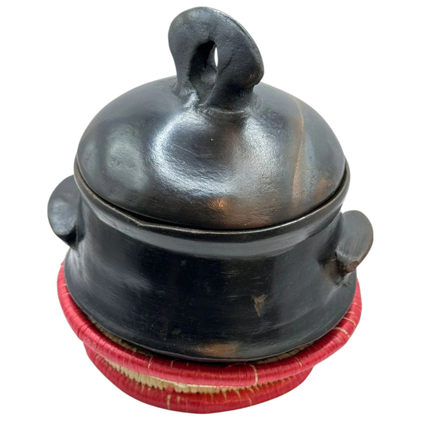 A traditional Habesha clay pottery stew bowl, known as Shekla, with a black and brown color and a hand holding palm leaf on the lid.
