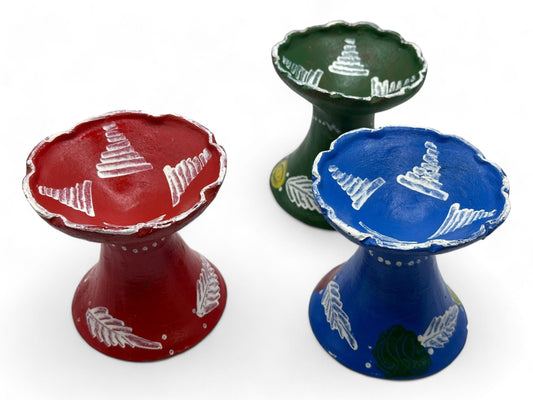 Three clay incense burners in red, green, and blue colors with white line patterns on the top surface.