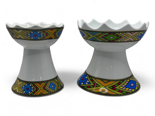 Two ceramic incense burners with geometric patterns in blue, yellow, and white colors.