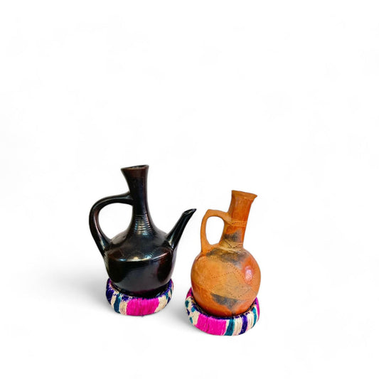 Two clay Jebena coffee pots with holders, one larger and one smaller, against a white background.