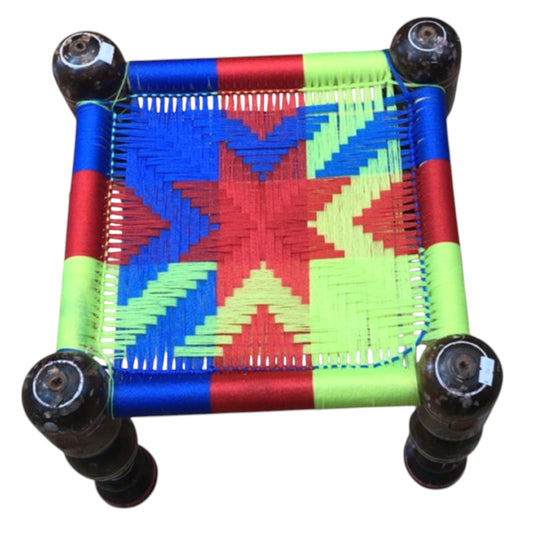 A multicolored geometric patterned handmade chair with wooden legs.